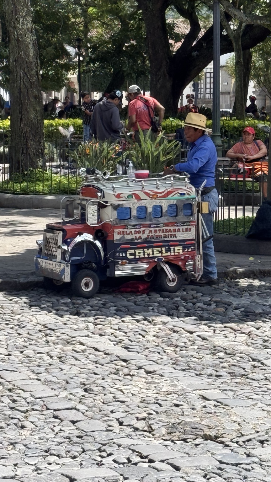 Photograph of a decorated Guatemalan ice cream bus cart on a cobblestone plaza